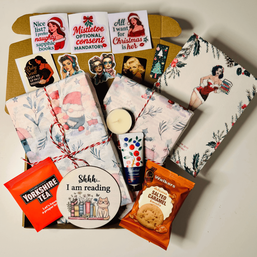 Festive lesbian gift box featuring lesbian romance book merchandise by lesbian romance fiction author Ruby Scott, including wrapped books, Christmas stickers with sapphic quotes, a candle, tea, biscuits, hand cream, and a “Shhh… I am reading” coaster — a cosy lesbian love story-themed Christmas bundle perfect for book lovers.