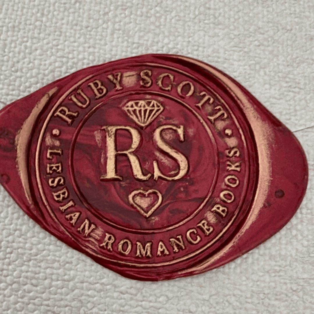 A bookish gift. A red and gold wax seal featuring the initials "RS" in the centre, a diamond icon above, and a heart below. The outer ring reads "Ruby Scott • Lesbian Romance Books" in embossed text.