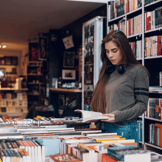 a woman looking at a pile of lesbian romance books in a library
