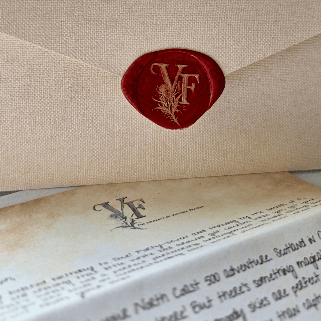 A red wax seal stamped with the initials "VF" and a botanical motif, securing a textured beige envelope. Below the envelope lies a vintage-style letter marked “The Property of Victoria Fraser,” with elegant handwriting and a faintly aged paper effect.