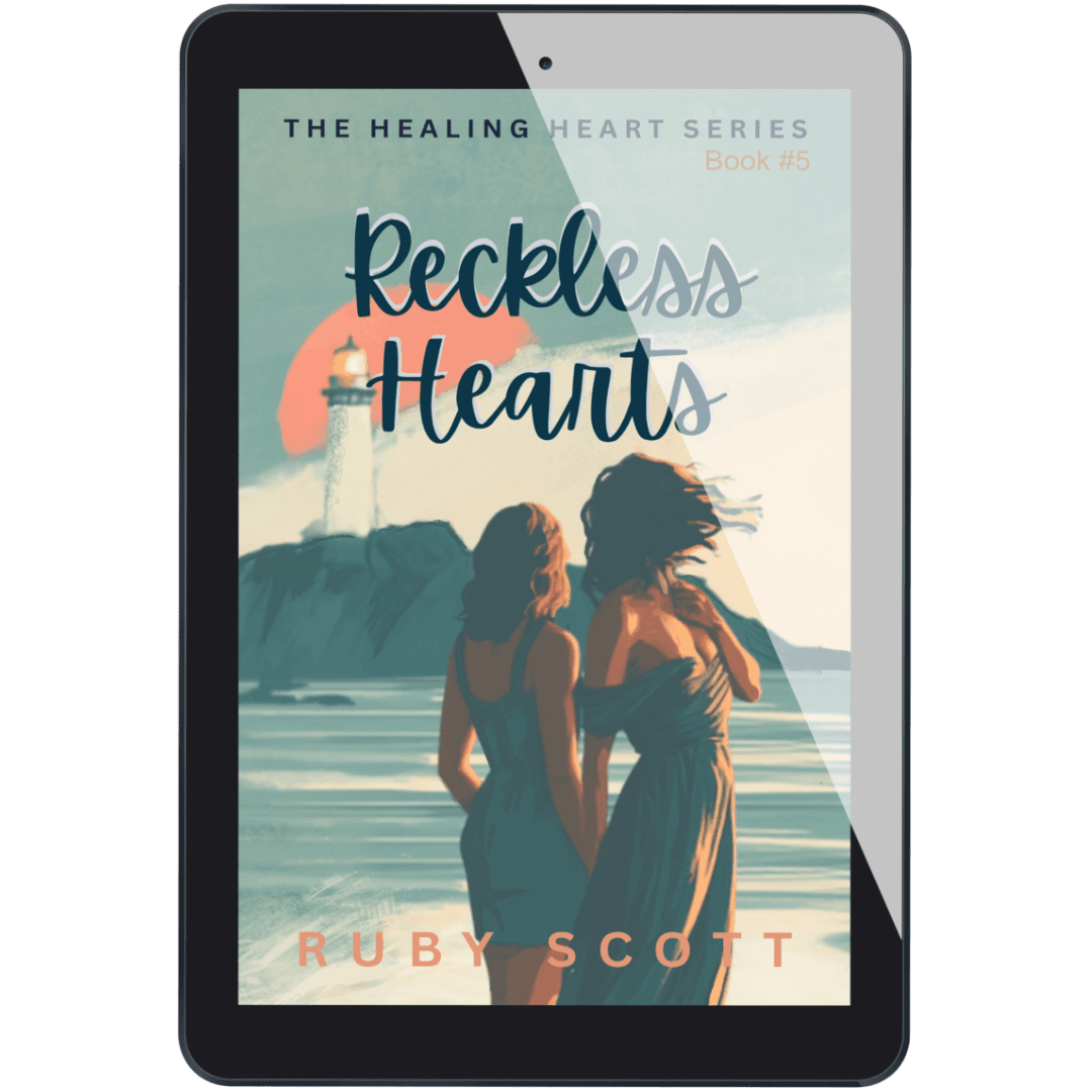 A tablet device displaying the book cover for 'Reckless Hearts, Book #5' by Ruby Scott. The cover art features an illustration of two women standing by the sea with a lighthouse and sunset in the background.