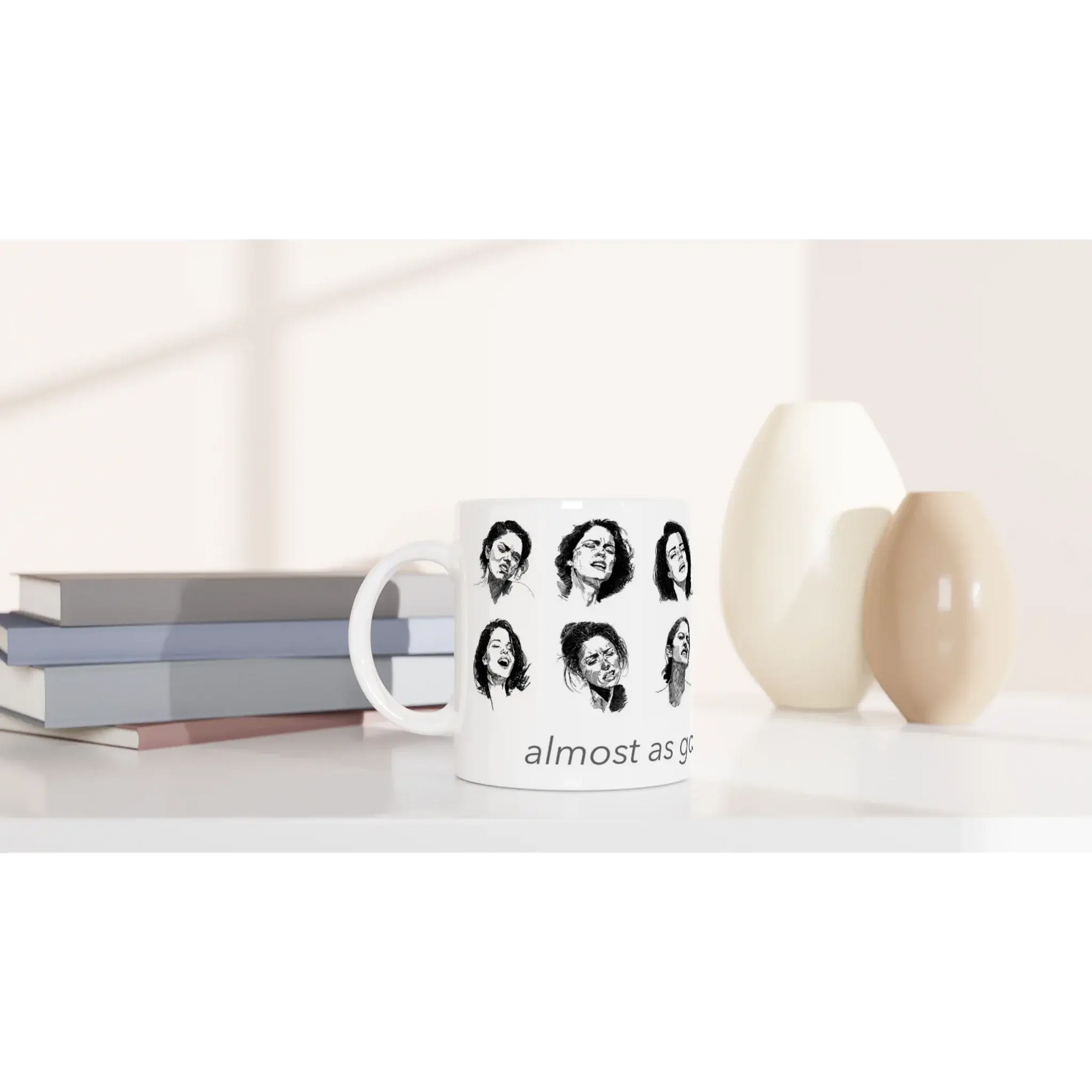 White ceramic mug featuring artistic portraits and the phrase 'almost as good as coffee' on a stylish table setting.