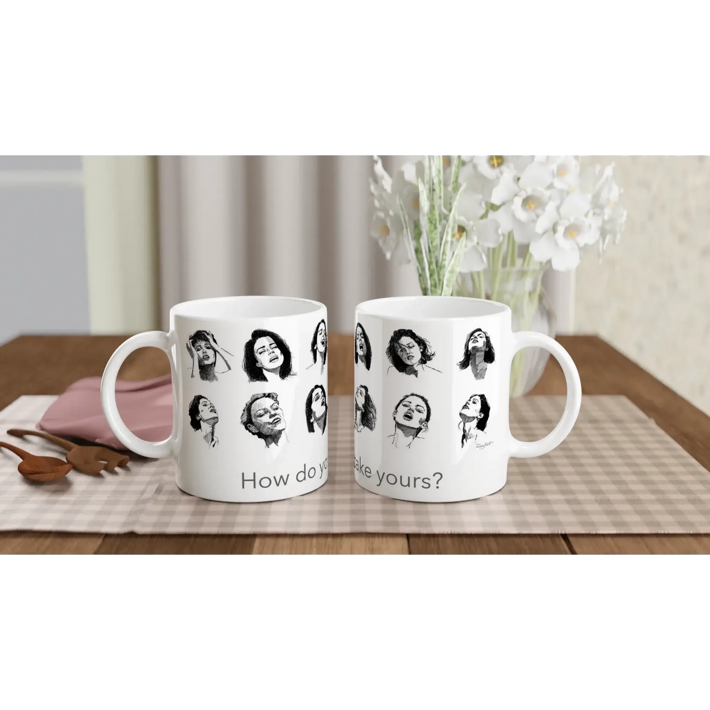 Smut reader mug with expressive illustrated faces, styled beside stacked books and neutral ceramic vases in a minimalist interior setting.