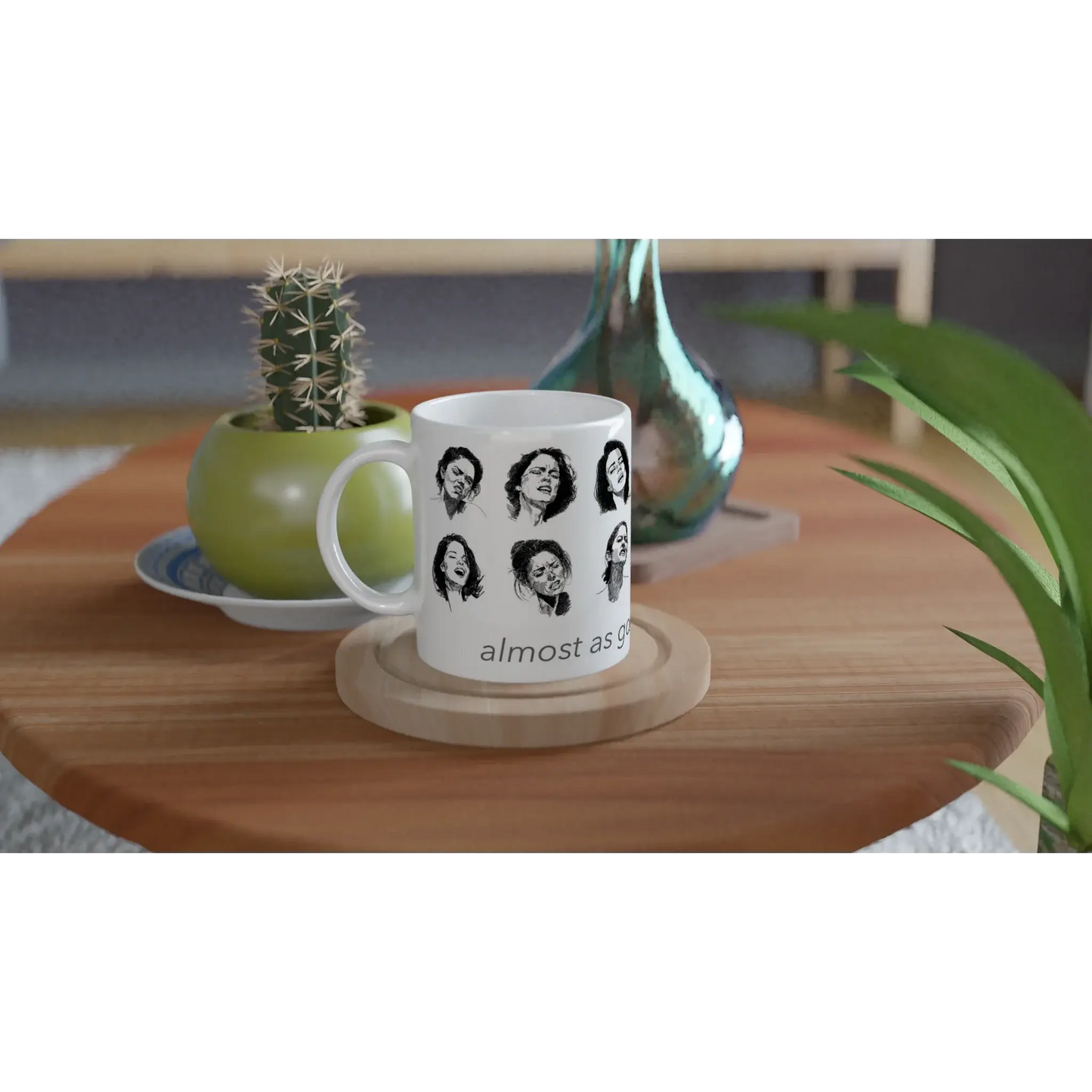 Smut reader mug in a styled living-room scene on a coaster, with a cactus and vase behind it, showing black and white illustrated faces and partial text.